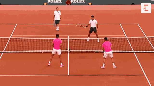 two men are playing tennis on a court with rolex advertisements on the wall behind them