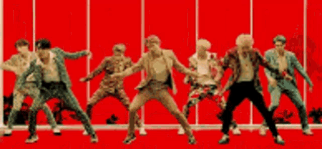 a group of people are standing in front of a red wall .