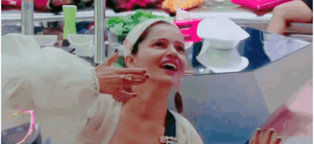 a woman with a headband on her head is laughing while getting her face checked by a doctor .