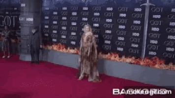 a woman stands on a red carpet in front of a wall that has got written on it