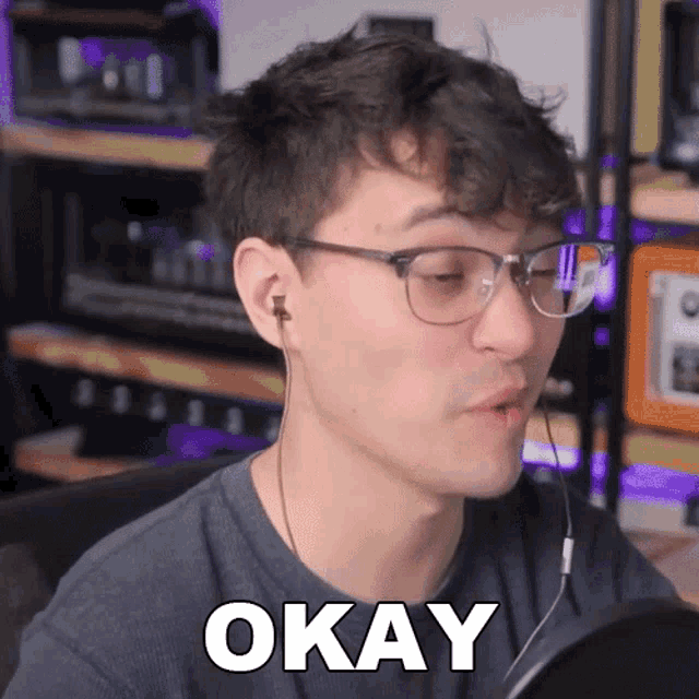 a man wearing glasses and ear buds is saying okay
