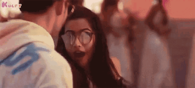 a man and a woman are standing next to each other in a crowd . the woman is wearing glasses .