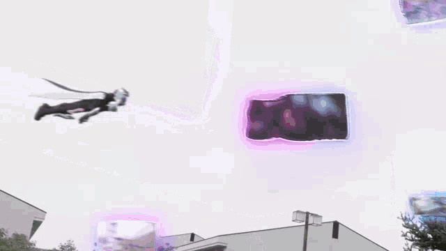 a person is flying through the air in front of a building with a purple light coming out of it .