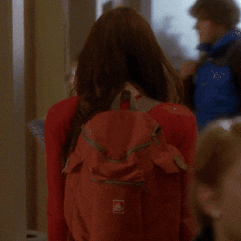a woman wearing a red backpack with the word columbia on it