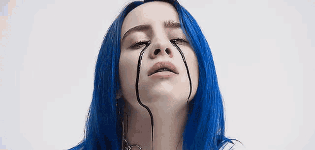 billie eilish with blue hair is crying with black tears coming out of her eyes .