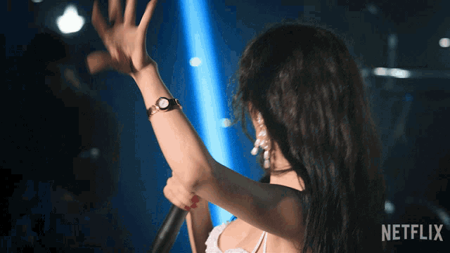a woman is singing into a microphone with a netflix logo in the background
