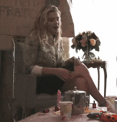 a woman sits at a table with a vase of flowers in front of a sign that says ' ferrari '