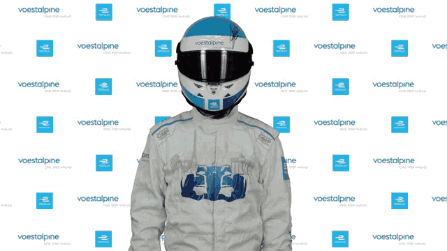 a man wearing a helmet with the word omp on it stands in front of a wall that says " voestalpine "