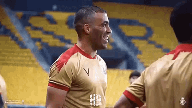 a man in a gold shirt with the letter v on the front