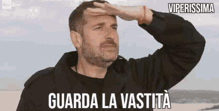 a man with a beard is covering his eyes with his hand and the words guarda la vastita are above him