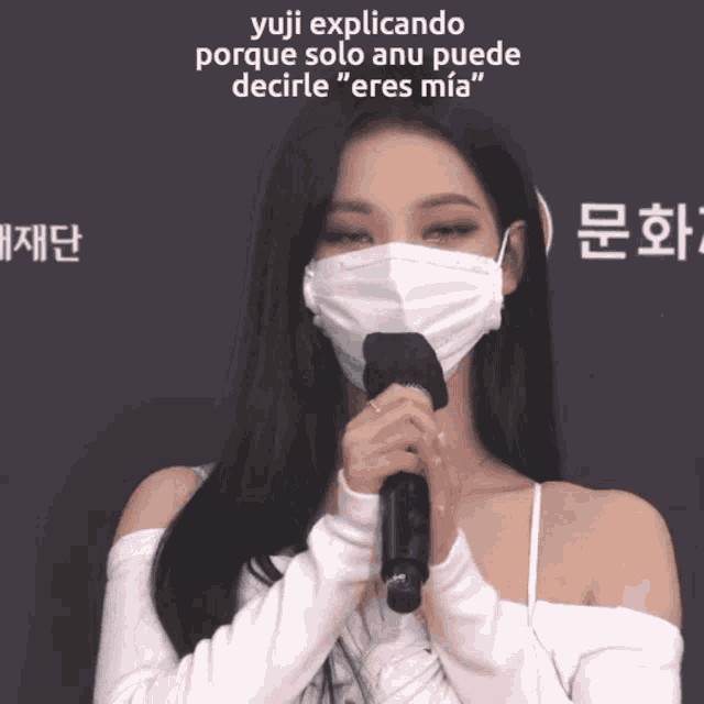 a woman wearing a mask holds a microphone and says " yuji explicando porque solo anu puede decirte "