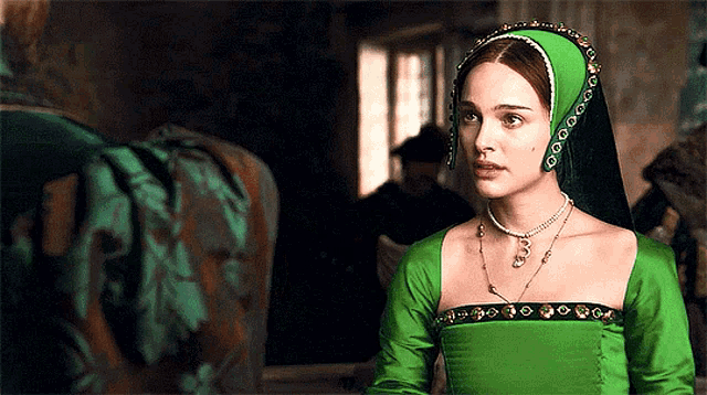 a woman wearing a green dress and a black headpiece