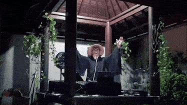 a man wearing a straw hat is sitting at a table with a laptop on it