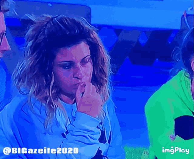a woman in a blue sweatshirt is sitting next to another woman in a green sweatshirt with imgplay written below her