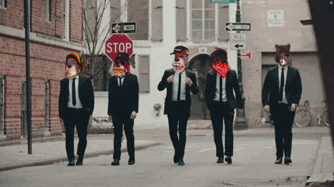 a group of men in suits are walking down a street with a stop sign in the background