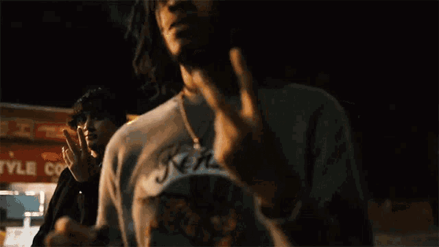 a man is giving the middle finger to another man in a dark room