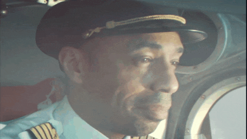 a man in a pilot 's uniform is looking out of a window