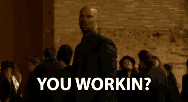 a man in a suit is standing in front of a crowd of people and asking if they work .