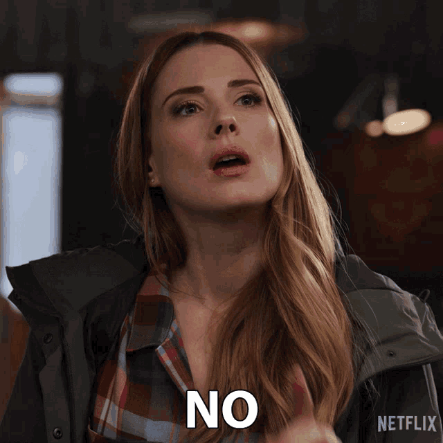 a woman wearing a plaid shirt and a green jacket says no