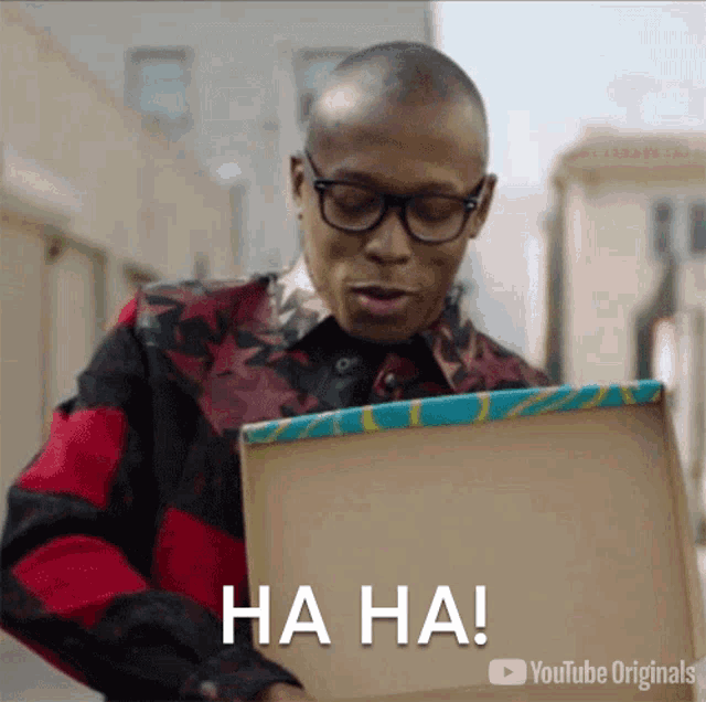 a man with glasses is holding a box that says ha ha on it