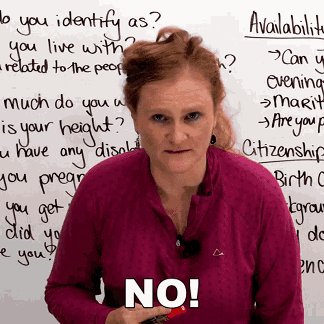a woman is standing in front of a white board with the word no on it