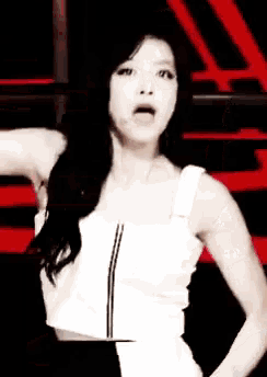 a woman in a white tank top is standing in front of a red and black background