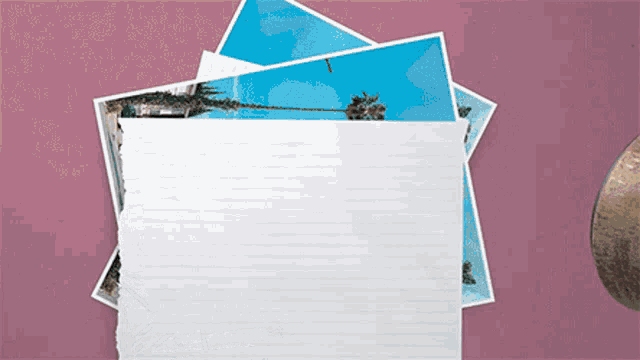 a stack of photographs on a pink background with a piece of paper missing
