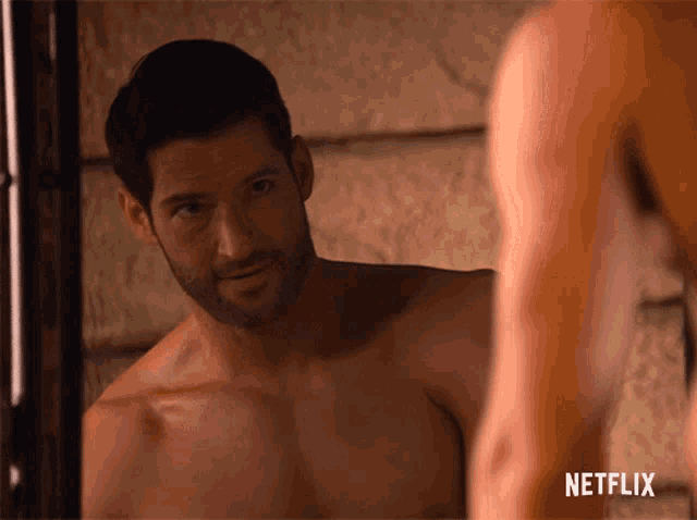 a shirtless man is looking at himself in a mirror with a netflix logo in the corner