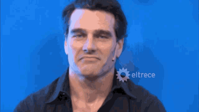 a man is making a face in front of a blue background with eltrece written on it