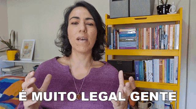 a woman is standing in front of a bookshelf and says e muito legal gente