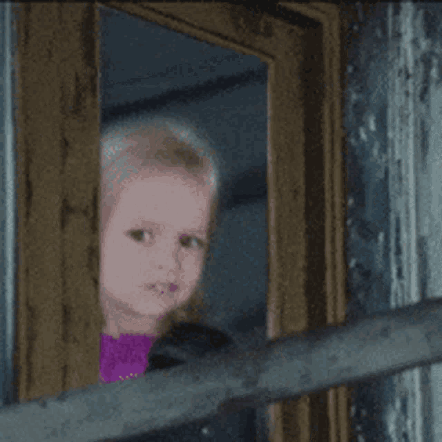 a little girl is looking out of a doorway