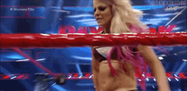 a woman is standing in a wrestling ring with a red rope around her waist .