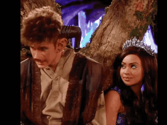 a man and woman are standing next to each other and the woman is wearing a tiara