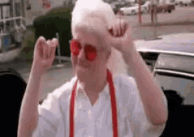 an elderly woman wearing red sunglasses and red suspenders .