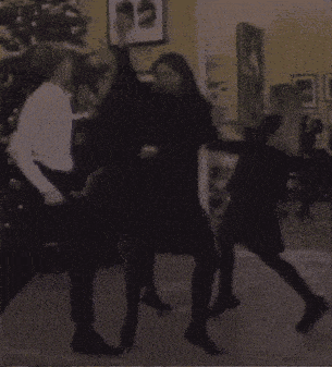 a group of people are dancing in a room with a christmas tree