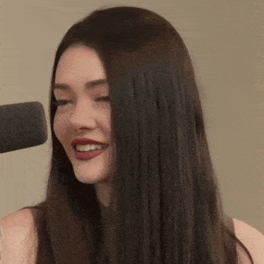a woman with long hair is smiling and holding her hair
