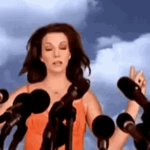 a woman is standing in front of a crowd of microphones and giving a speech .