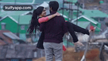 a man is carrying a woman in his arms in a city .