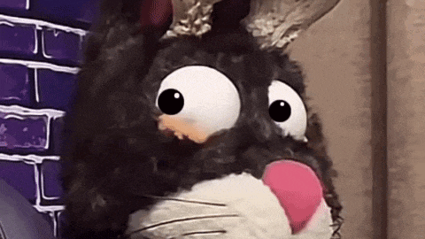 a stuffed animal with big eyes and a pink nose is looking at the camera .