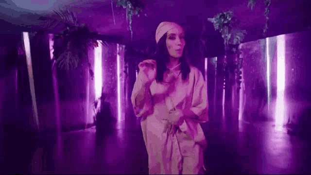 a woman in a pink dress is dancing in a purple room with purple lights .