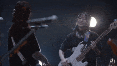 two girls are playing guitars and singing into microphones on stage