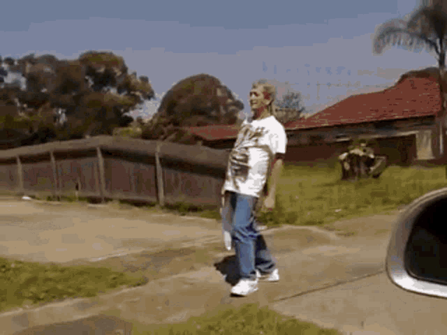 a man wearing a white shirt that says ' a ' on it is walking down a sidewalk