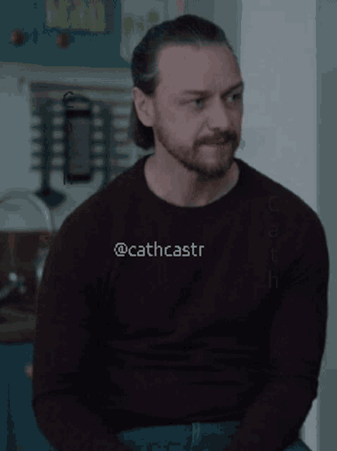 a man with a beard is wearing a purple sweater that says @cathcastr on it