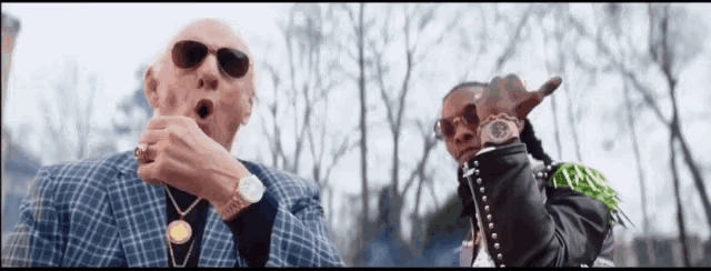 two men are standing next to each other and one of them is wearing a watch .