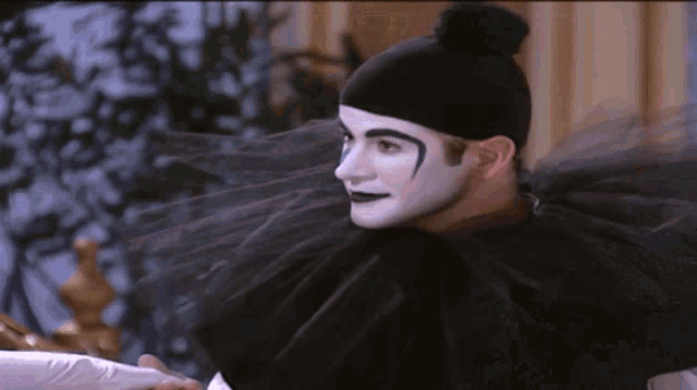 a man dressed as a clown with white face paint