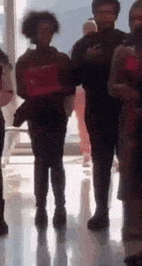 a group of people standing next to each other in a hallway .