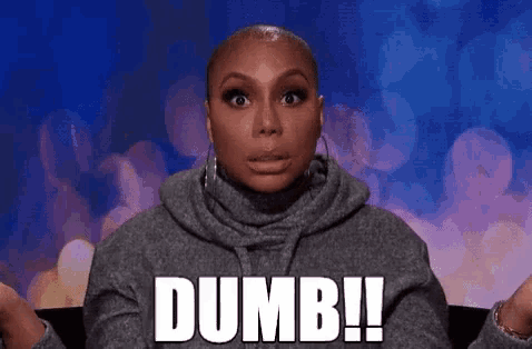 a woman in a grey sweater is saying the word dumb