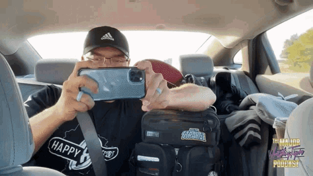 a man is taking a picture in the back seat of a car with a bag that says ' strange ' on it