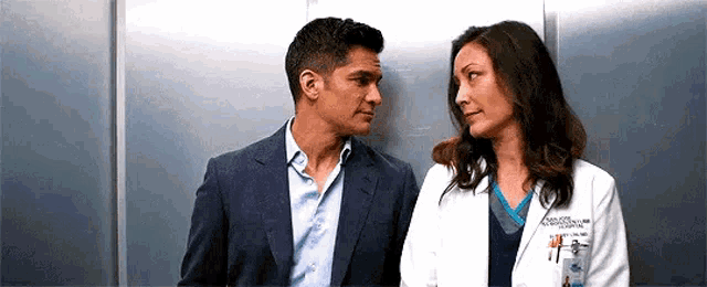 a man and a woman are looking at each other in an elevator .