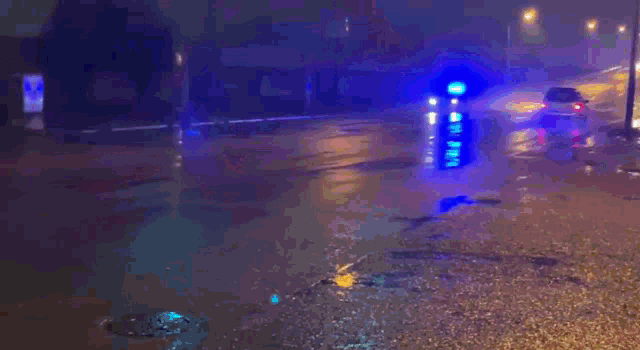 a police car is driving down a wet road at night